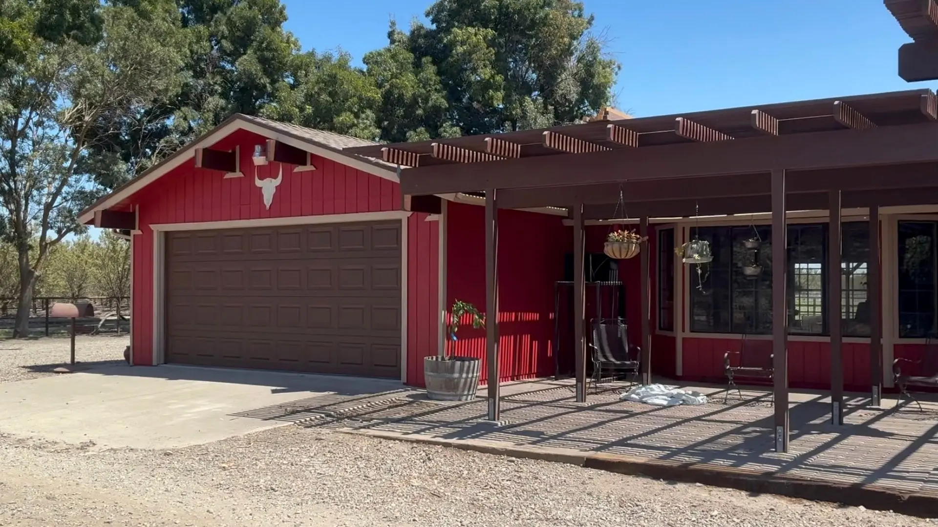 Freshly restored red home exterior with brown garage doors and pergola by BRT Painting